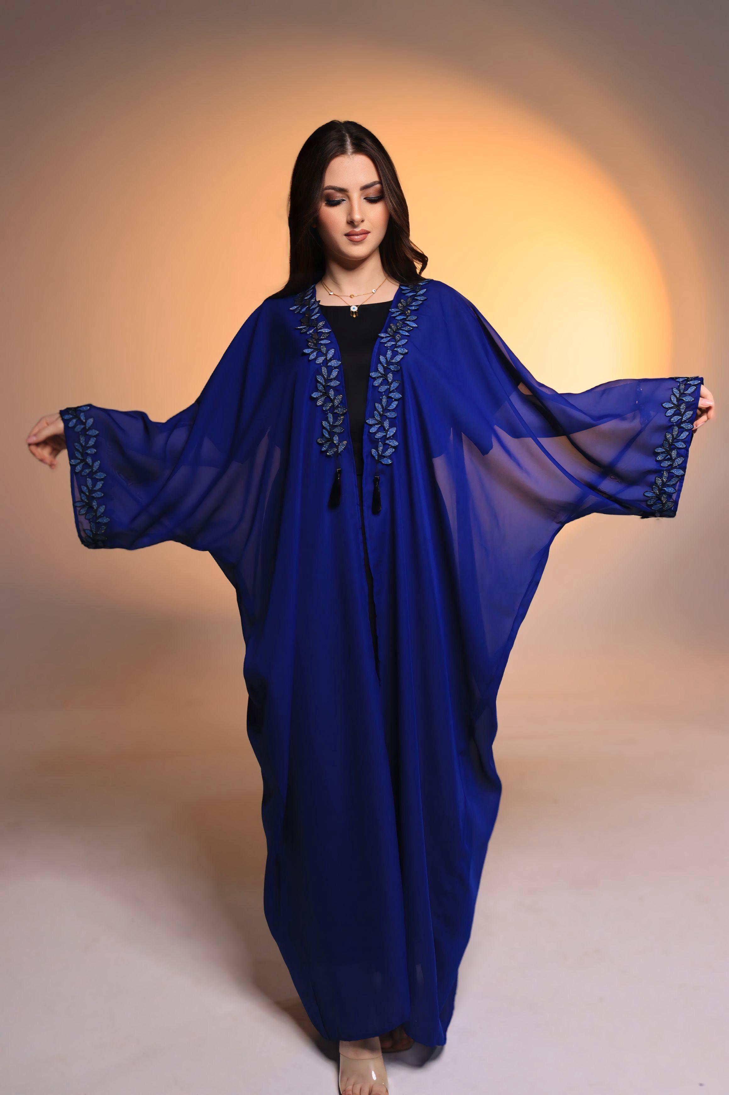 Woman wearing a blue embroidered dress against a warm-toned background