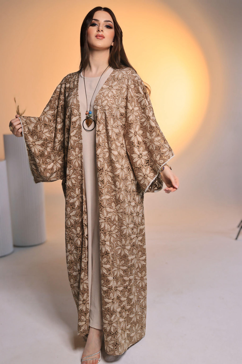 Woman wearing a long, patterned dress against a neutral background