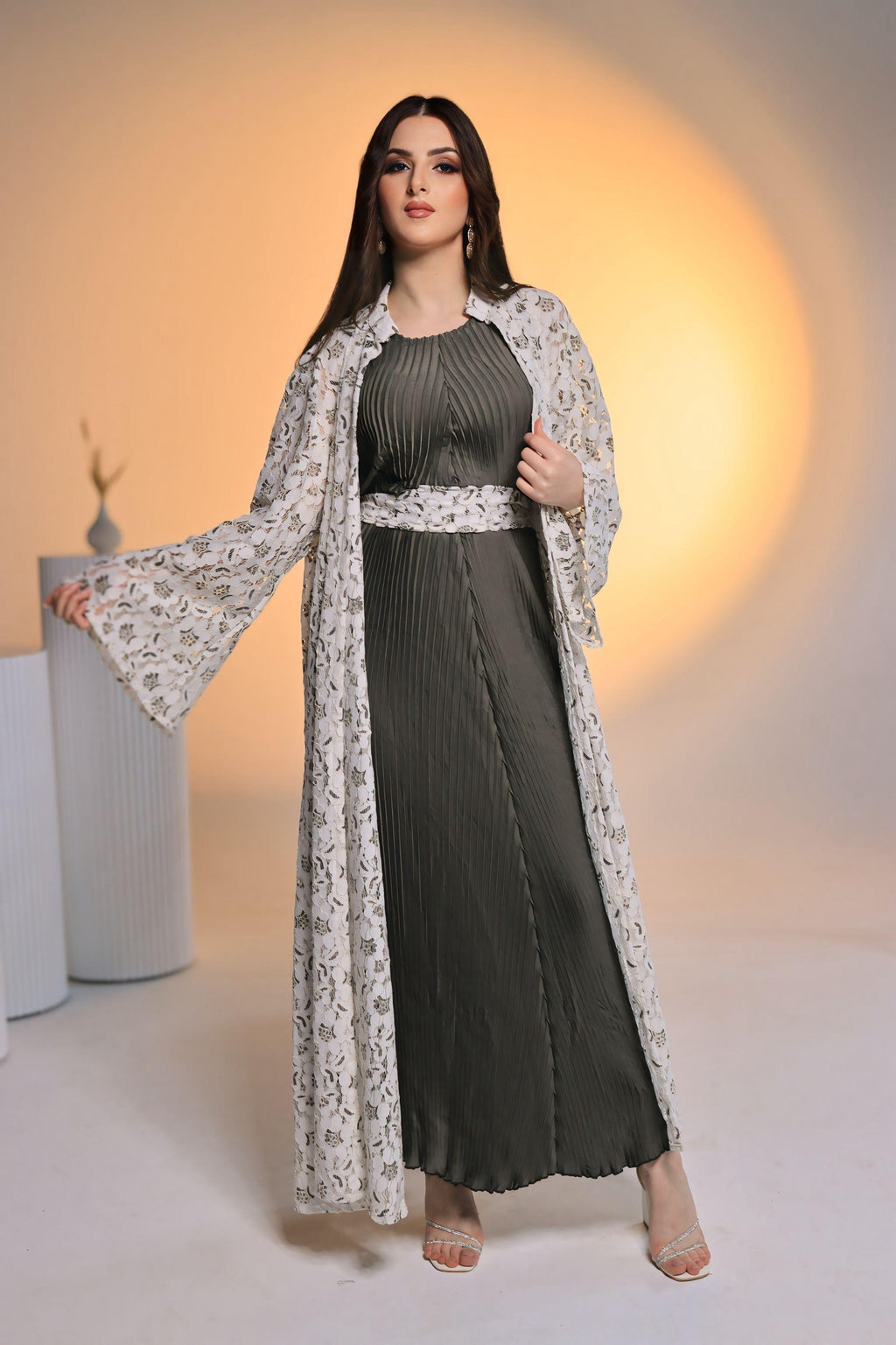 Woman wearing a long dark dress with a light floral shawl against a warm-toned background