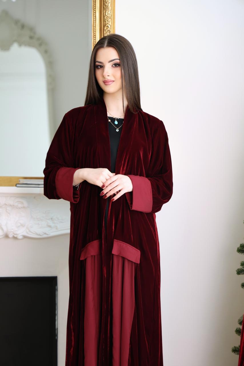 Woman wearing a burgundy velvet robe in a room with a mirror and decorative elements.