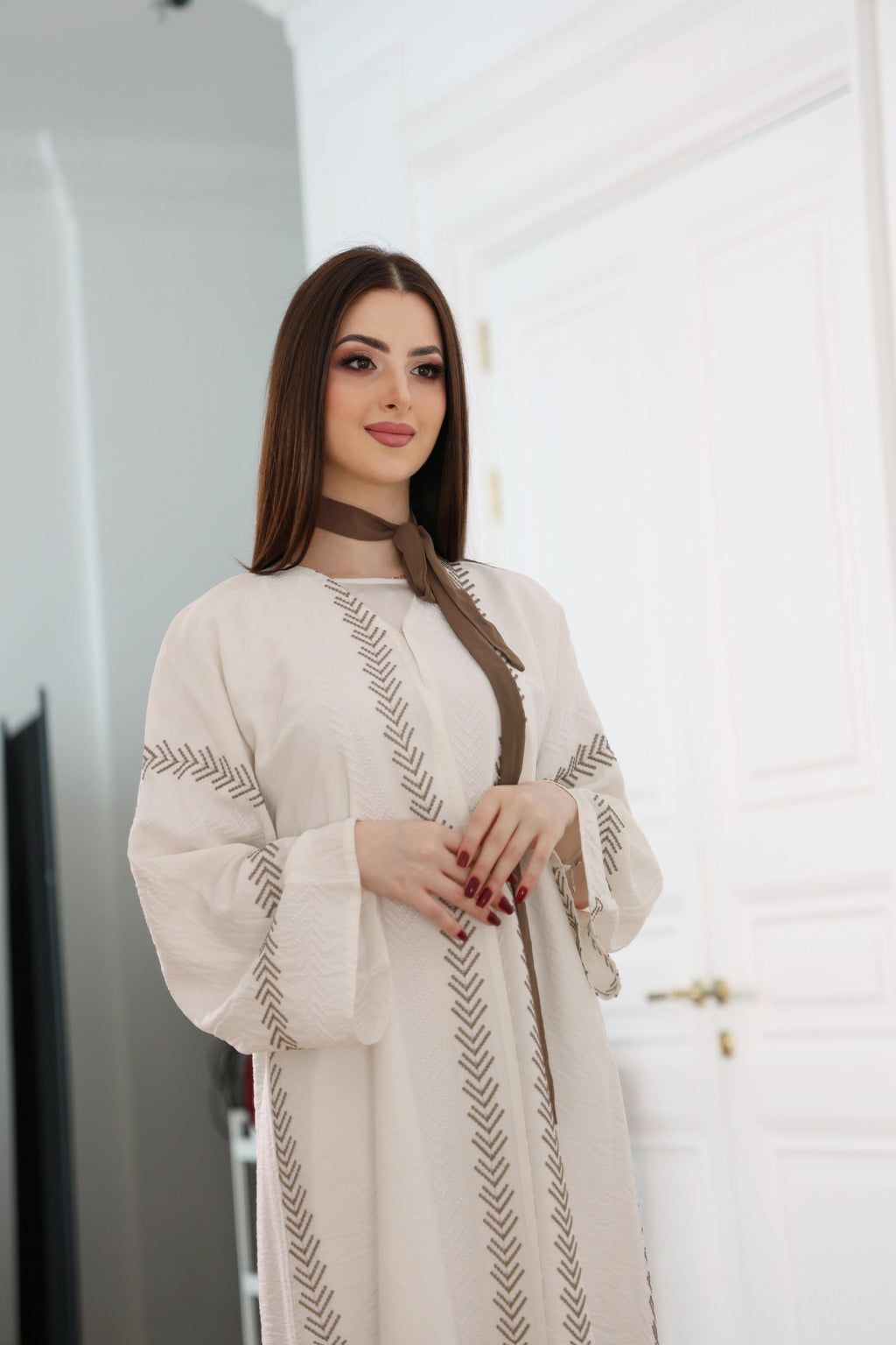 Woman wearing a cream-colored embroidered dress in an indoor setting