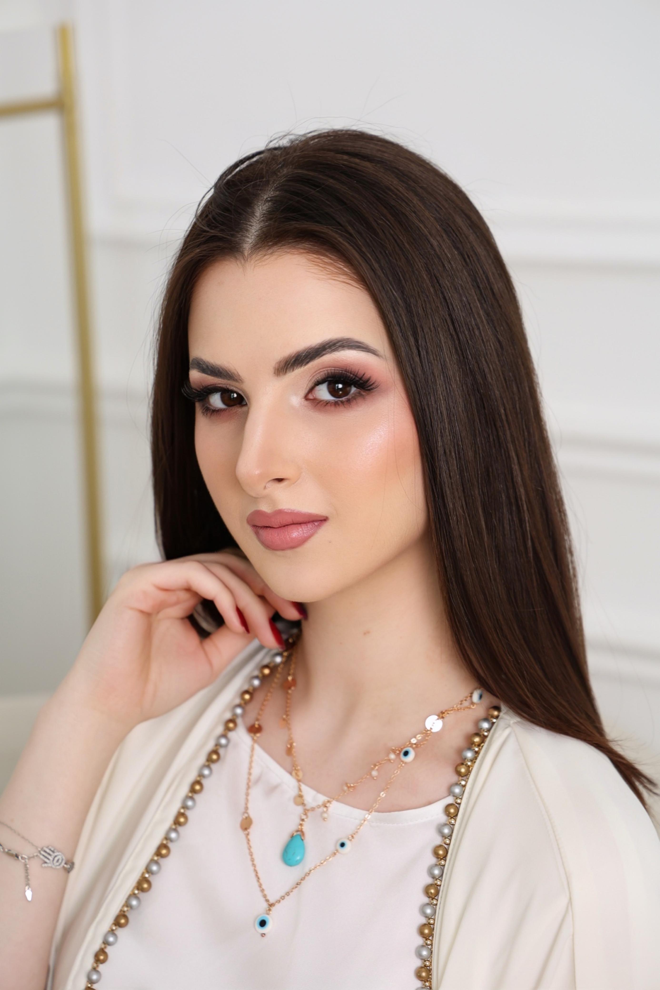 Woman wearing a white outfit with jewelry against a neutral background