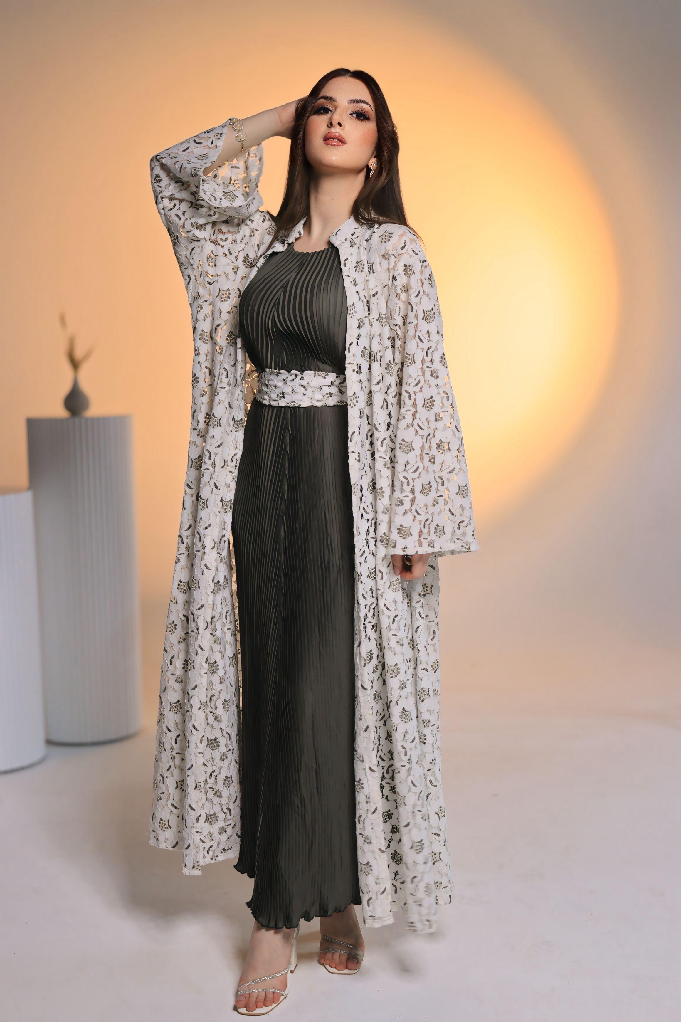Woman wearing a black dress with a floral cover-up against a warm-toned background